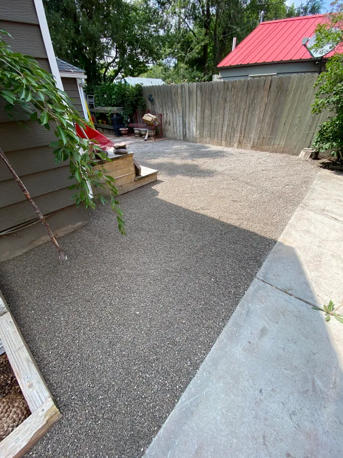 The same side yard as a clean aggregate pad along the house.