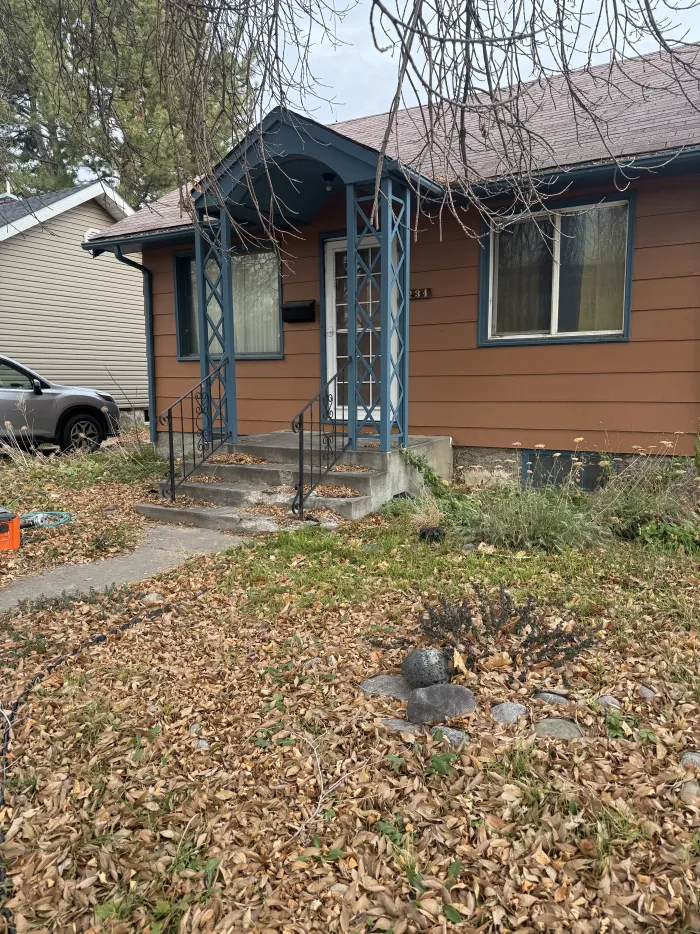 The front entry of an orange house with a small porch and leaves on the ground.
